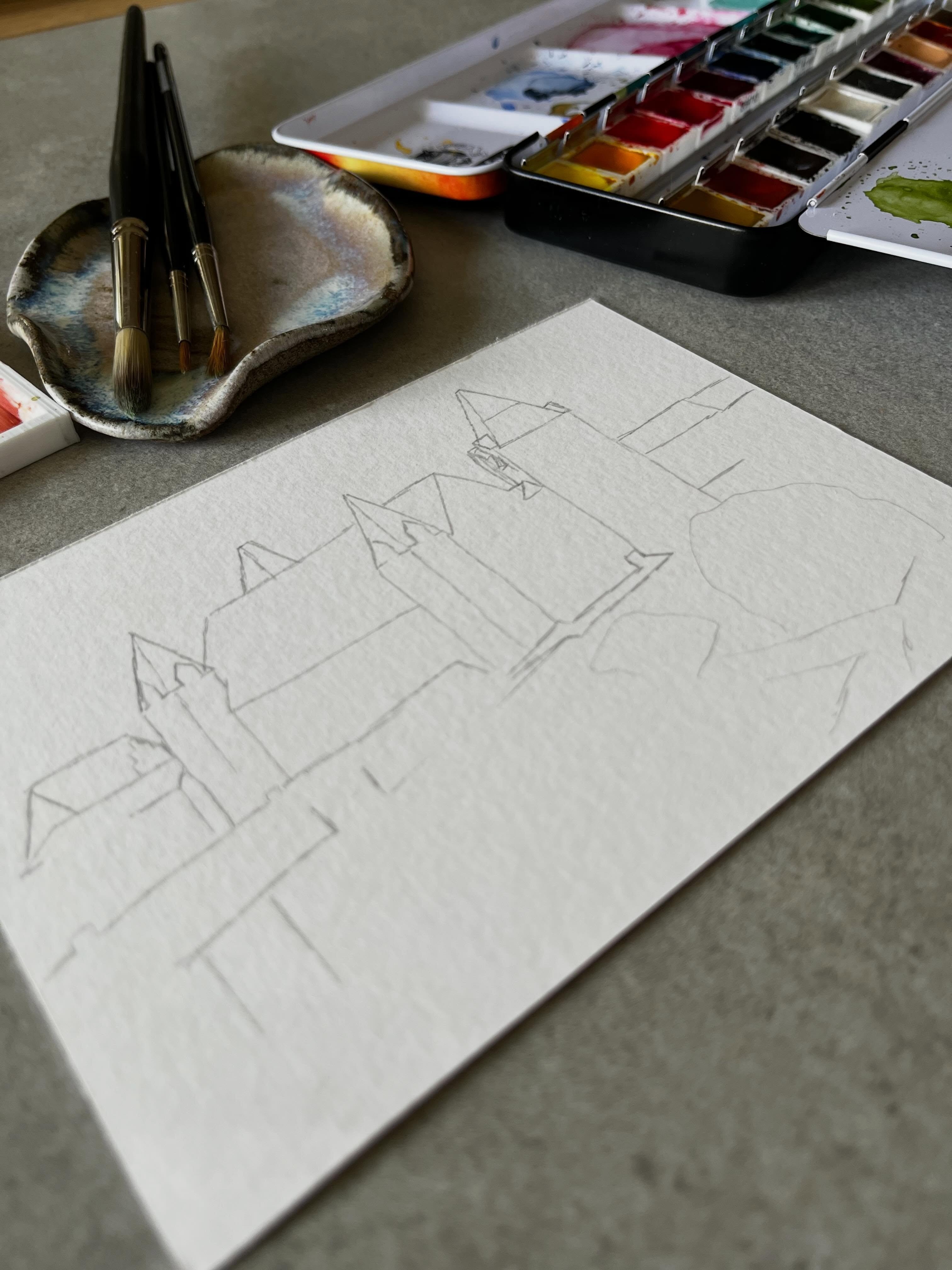 Aquarell-Skizze, Pinsel und Farbpalette auf dem Arbeitstisch
